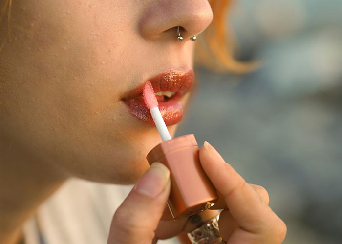 Close-up of woman applying lip gloss, illustrating changes in preferences women stopped pretending they like after 30.