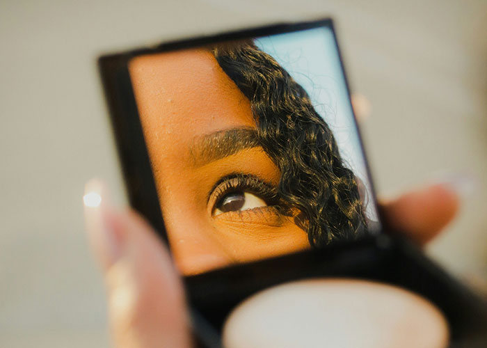 Close-up of a woman's eye reflected in a compact mirror, symbolizing confidence and things women stopped pretending to like after 30