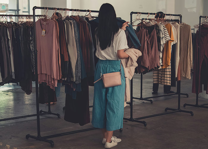 Woman browsing clothes on racks in a store, reflecting fashion and preferences women stopped pretending they like after 30.