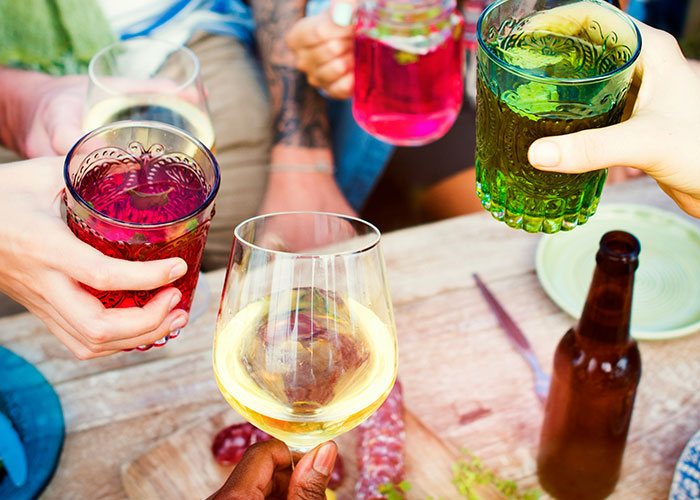 Hands holding colorful drinks in a toast, reflecting lifestyle changes women stopped pretending they like after 30.