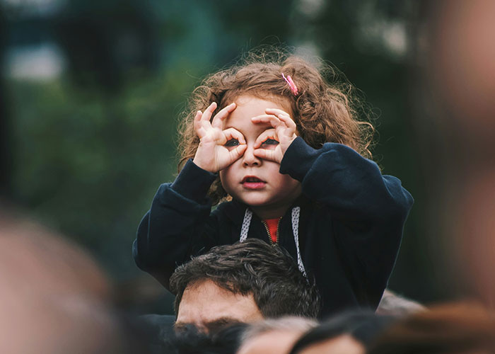 Young girl with curly hair making binocular shapes with her hands, symbolizing things women stopped pretending they like after 30.