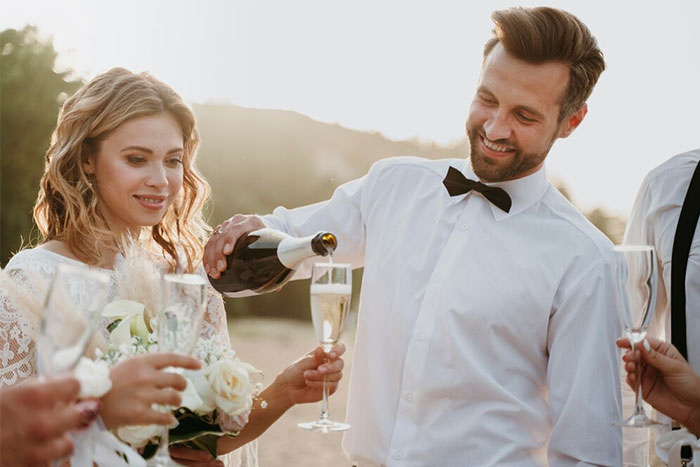 Couple celebrating at a wedding with champagne, capturing a moment related to stopping a boyfriend&rsquo;s proposal.