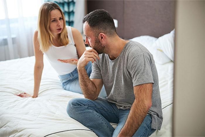 Couple having a serious argument on bed, illustrating tension around stopping boyfriend&rsquo;s proposal at wedding.