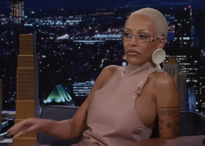 Woman with short blonde hair and glasses sharing stories about people who knew celebrities before fame on a talk show.