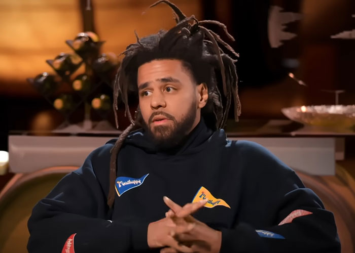 Man with dreadlocks in a dark hoodie sharing stories about people who knew celebrities before fame in an interview setting.