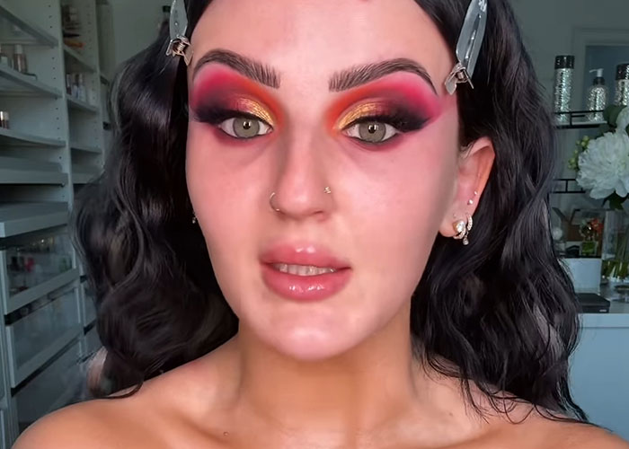 Young woman with dramatic colorful eye makeup revealing celebrity personality before fame in casual indoor setting.