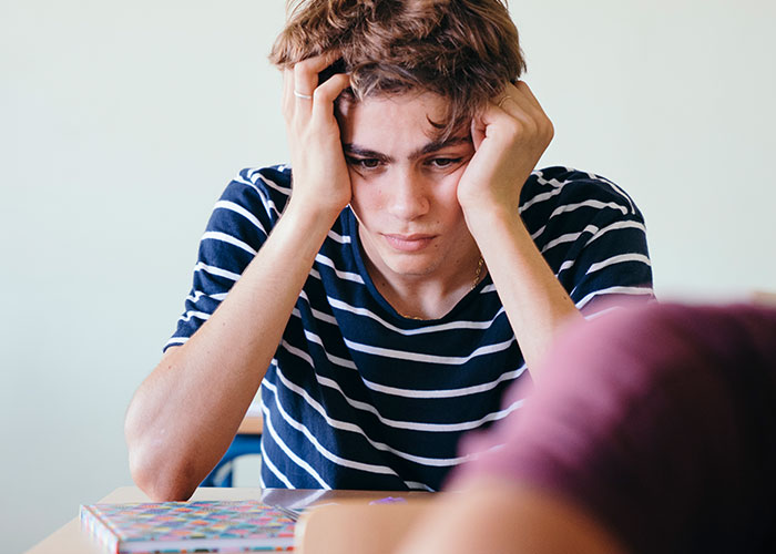 Student in striped shirt looking stressed during quiz, illustrating teacher catching cheaters with multiple quiz versions.