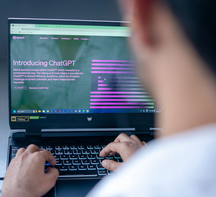 Person typing on a laptop displaying ChatGPT introduction page related to 2025 summer reading list and book existence issues.