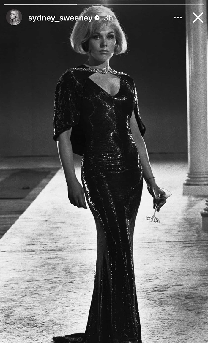 Sydney Sweeney wearing a sleek black gown, holding a glass, with a vintage Hollywood glamour style at the Met Gala.