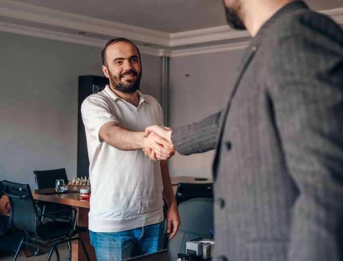 Two men shaking hands in an office, illustrating real-life cheat codes for successful interactions and agreements.