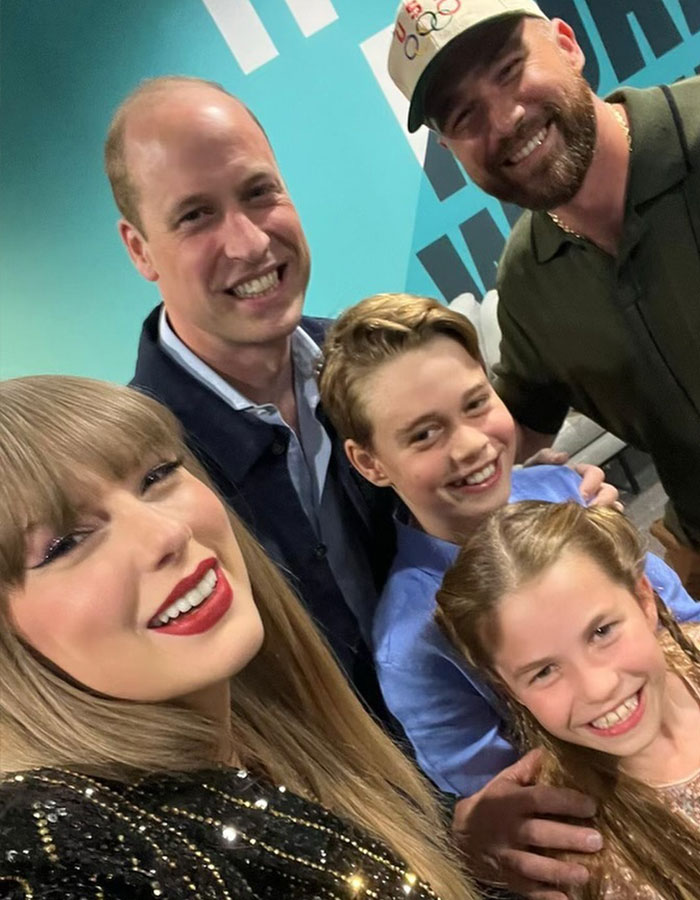 Taylor Swift smiling with a group of people, illustrating the topic of Trump claims about Taylor Swift being no longer hot.