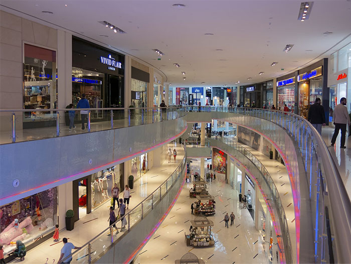 Modern shopping mall interior with multiple levels, showcasing stores and shoppers exploring potential red flag gifts.