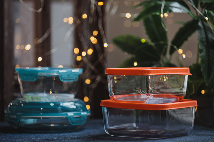 Stacked glass food storage containers with colorful lids on a table suggesting everyday household gifts as red flags.