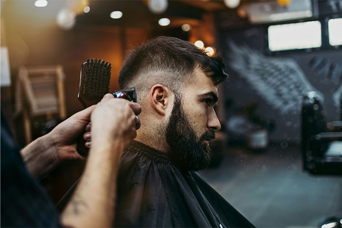 Man with beard getting a haircut in a barbershop, illustrating red flag gifts from partners before divorce.