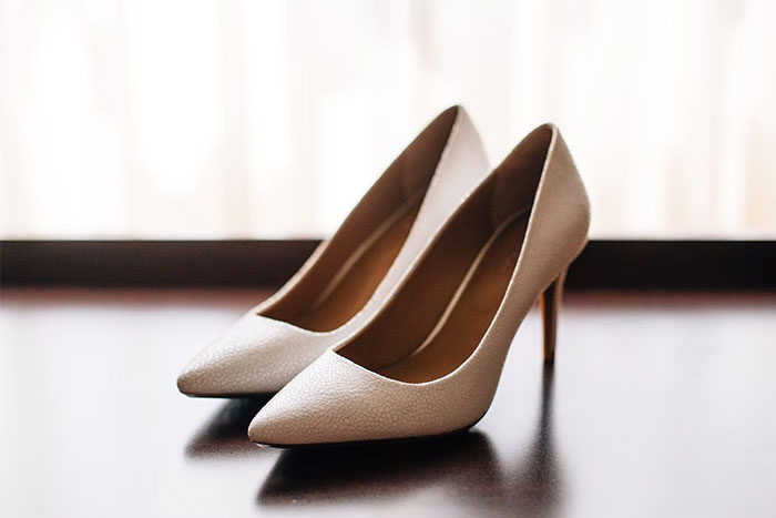 Beige high-heeled shoes placed on a dark surface, representing one of the terrible gifts from partners.