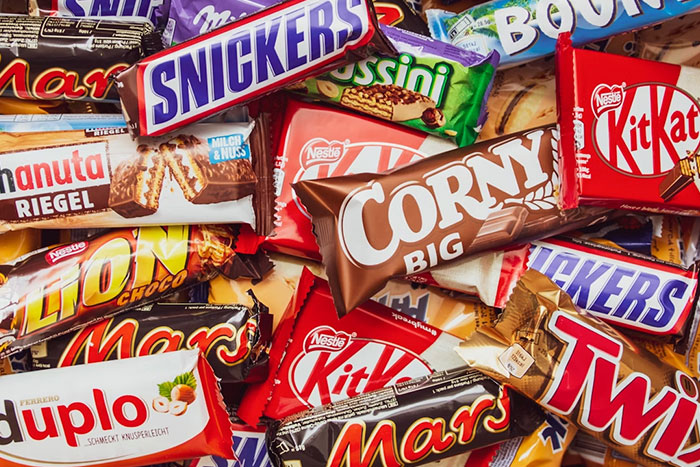 Assortment of popular candy bars including Snickers, KitKat, Mars, and Twix, symbolizing gift red flags in relationships.