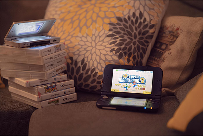 Stack of Nintendo DS game cases and two handheld consoles on a couch symbolizing gifts that were a red flag in relationships.