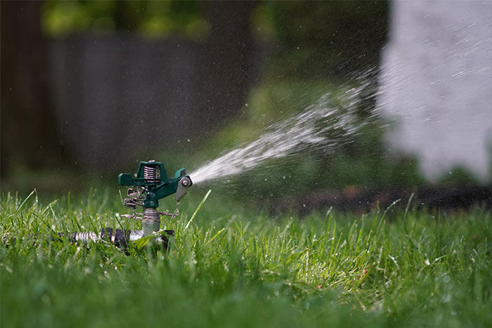 Garden sprinkler spraying water over green grass, symbolizing red flag gifts from partners after divorce.