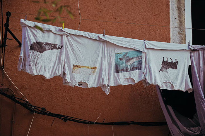 White graphic t-shirts hanging on a clothesline outside against an orange wall, representing gifts and red flags in relationships.