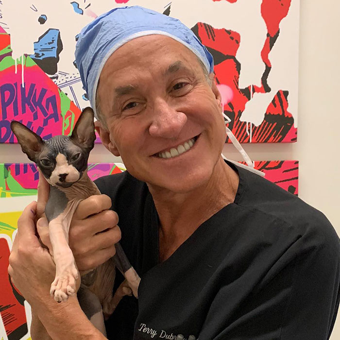 Man in medical scrubs holding a hairless cat, smiling, illustrating concerns about Ozempic tongue side effects from weight-loss meds.