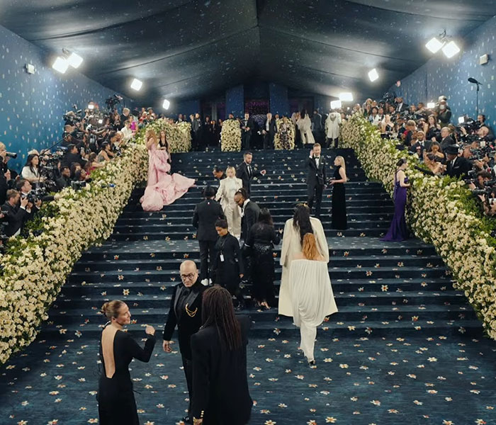 Crowded Met Gala stairs scene with attendees and photographers capturing the guy creating massive thirst in Lana Del Rey photo.