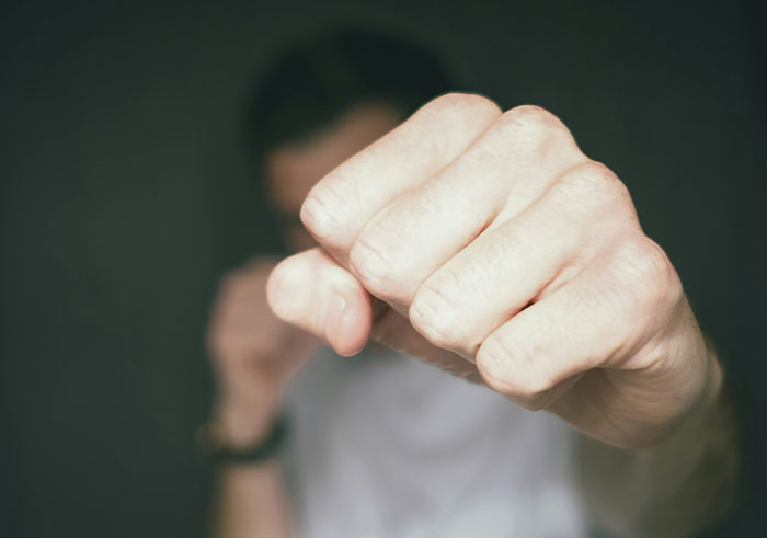 Man throwing a punch with focus on fist, illustrating sudden actions that could completely destroy people’s lives in seconds