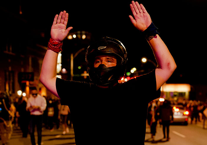Person wearing a helmet with hands raised during a nighttime street scene, illustrating risks that could destroy lives in seconds.