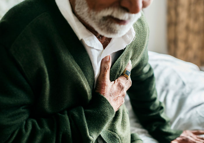 Elderly man clutching his chest in pain, illustrating sudden events that could completely destroy lives in seconds.