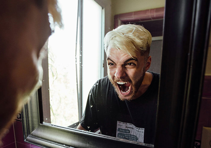 A young man angrily shouting at his reflection, illustrating the sudden impact of things that could destroy lives.