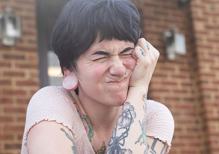 Person with tattoos and piercings making a distressed face, illustrating things that could destroy people's lives quickly.