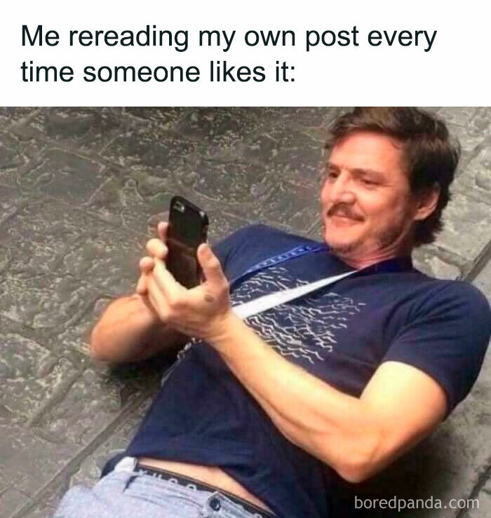 Man lying on the ground smiling at his phone, illustrating memes encapsulating the human experience with humor and relatability.