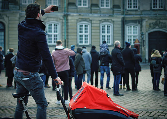 Man with a stroller taking a photo outdoors among a group of people, illustrating emergency personnel insights and crowd behavior.