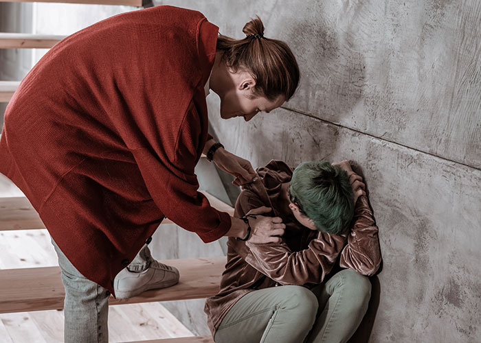 Emergency personnel assisting a distressed person sitting on stairs, showing care and support in a crisis situation.