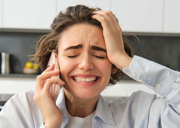 Stressed woman anxiously speaking on phone in kitchen, illustrating emergency personnel communication during crises.