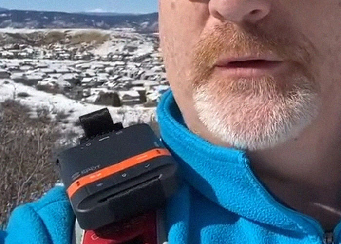 Close-up of emergency personnel wearing a communication device outdoors in a snowy mountainous area.