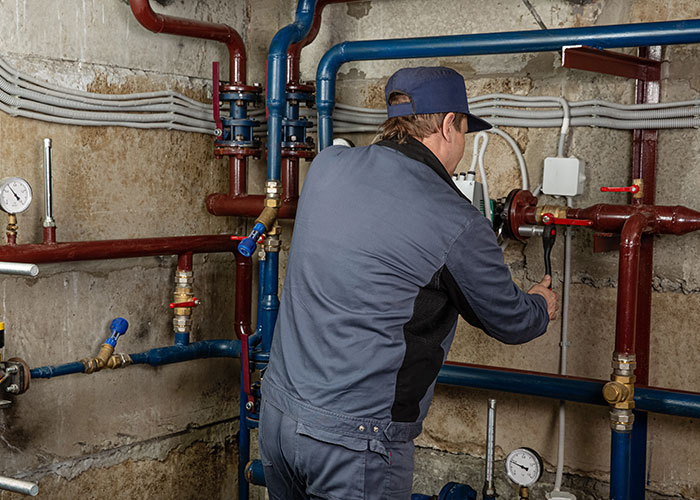 Emergency personnel inspecting pipes and valves in a utility room for safety and maintenance purposes