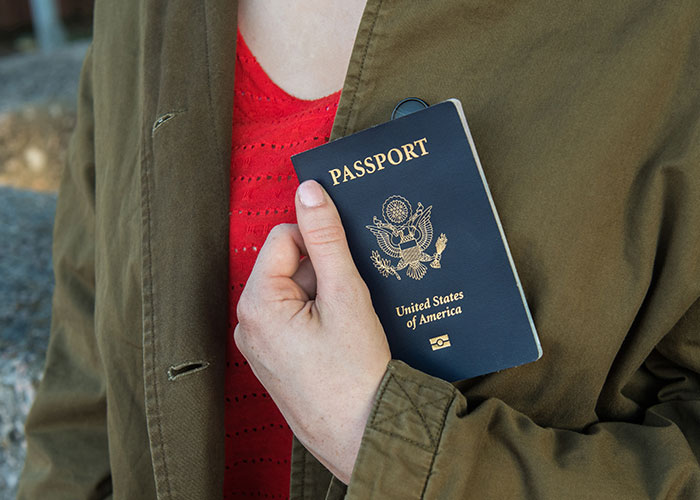 Person holding a United States passport close to their chest, representing emergency personnel preparedness and identity.