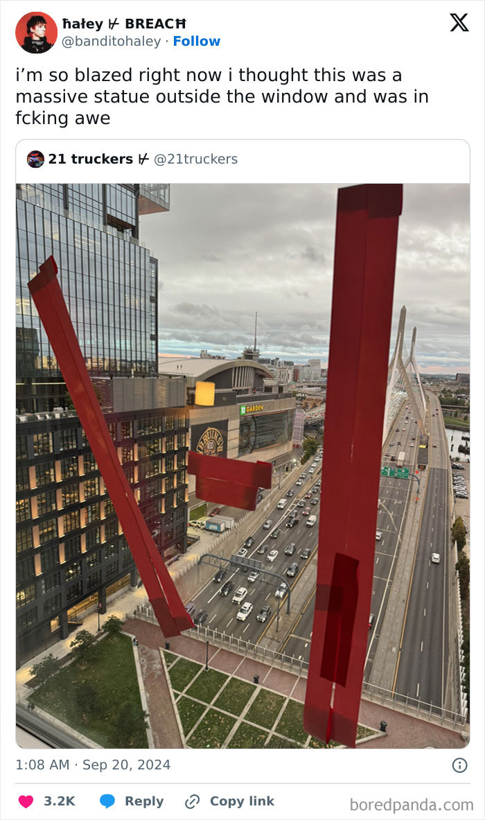 View of a city street and bridge seen through window stickers that look like a massive red sculpture outside, interesting things double take.