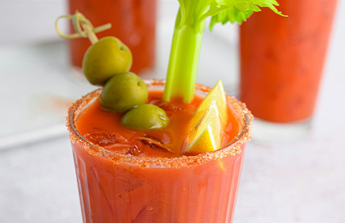 Bloody Mary cocktail garnished with olives, lemon wedge, and celery, related to experiences people regret trying.