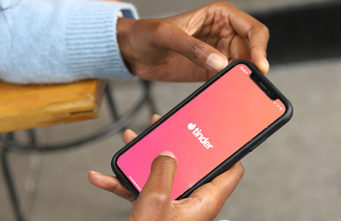Person holding smartphone with Tinder app open, illustrating one of the experiences that made people say never doing that again.