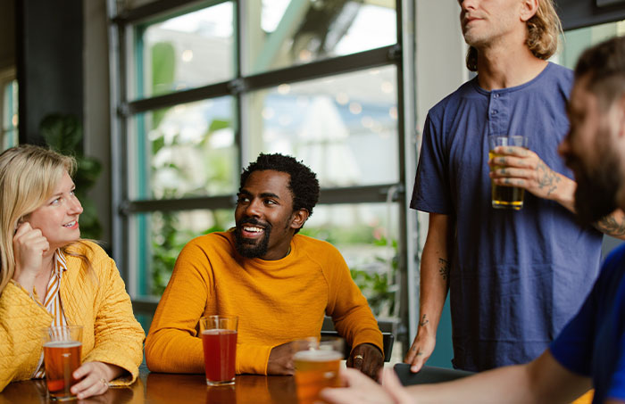 Group of friends sharing drinks and laughter at a casual gathering, reflecting on experiences never doing that again.