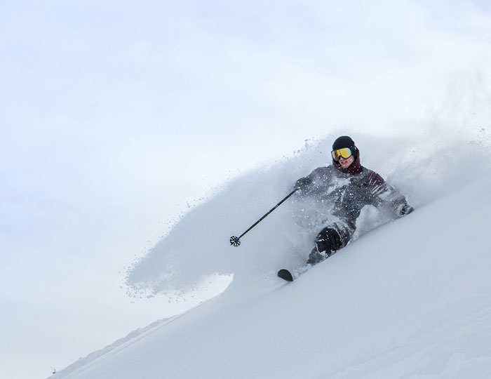 Skier plunging through deep snow on a steep slope, one of the risky experiences people say never doing again.