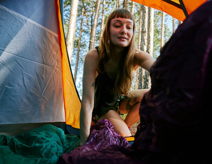 Young woman inside a camping tent, unpacking gear during an outdoor experience that made people say never doing that again.