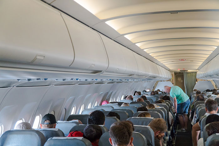 Airplane cabin interior with passengers seated as a mom defends her toddler from an angry passenger mid-flight. Airplane cabin interior with passengers seated as a mom defends her toddler from an angry passenger mid-flight.