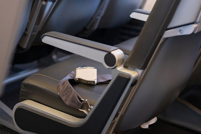 Empty airplane seat with fastened seatbelt highlighting a mom defending her toddler mid-flight situation. Empty airplane seat with fastened seatbelt highlighting a mom defending her toddler mid-flight situation.