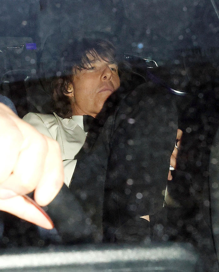 Tom Cruise sitting in a car wearing a white jacket at David Beckham's 50th birthday party event at night. Tom Cruise sitting in a car wearing a white jacket at David Beckham's 50th birthday party event at night.
