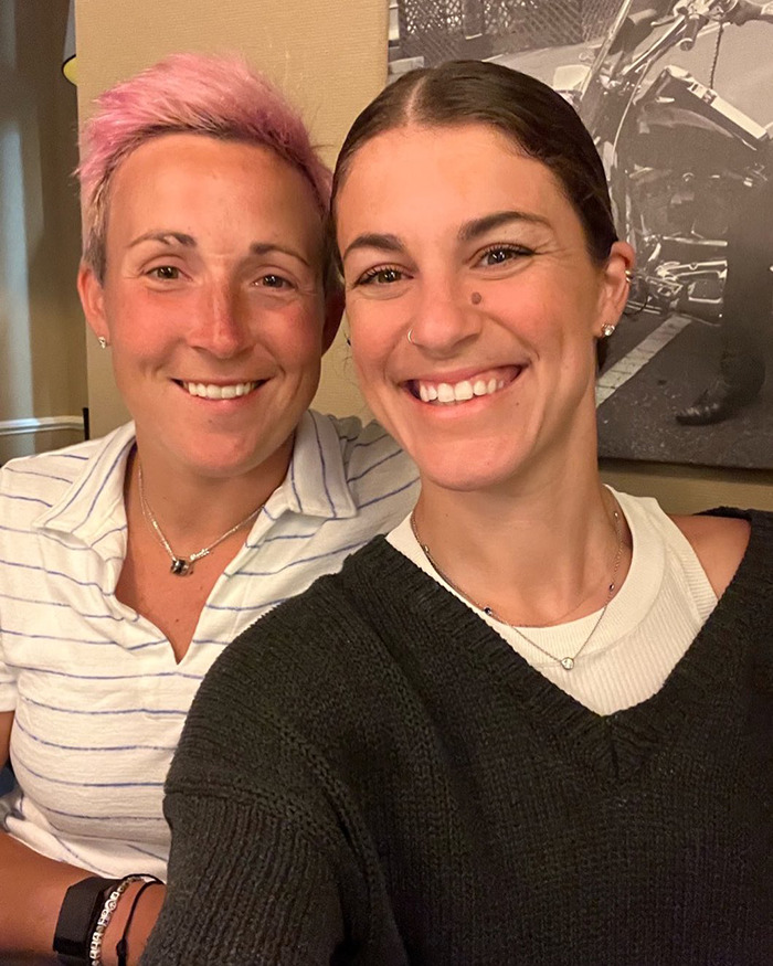 Two smiling women indoors, one with short pink hair, illustrating a female athlete mistaken for a man by restroom attendant.