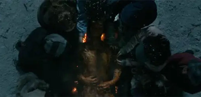 Dark scene showing a person lying down surrounded by others, illustrating horrifying behind-the-scenes movie facts.