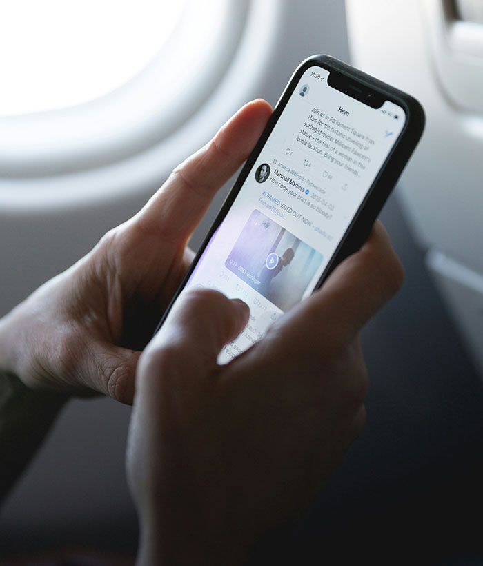 Person holding smartphone showing social media app, illustrating father of four with 37 followers jailed over deleted tweet.