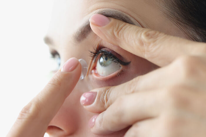 Close-up of a person inserting a contact lens, illustrating an example of incredibly unhealthy habits seen by others.